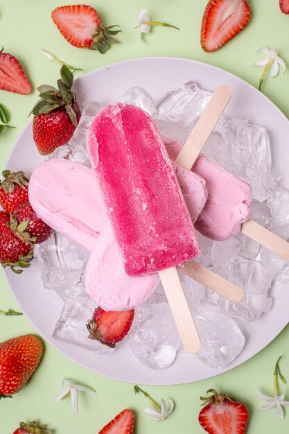 Ice cream on sticks and strawberries in surroundings