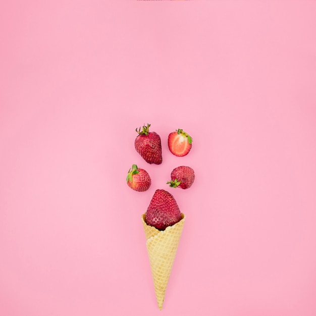 Ice cream waffle cone with strawberry on light surface