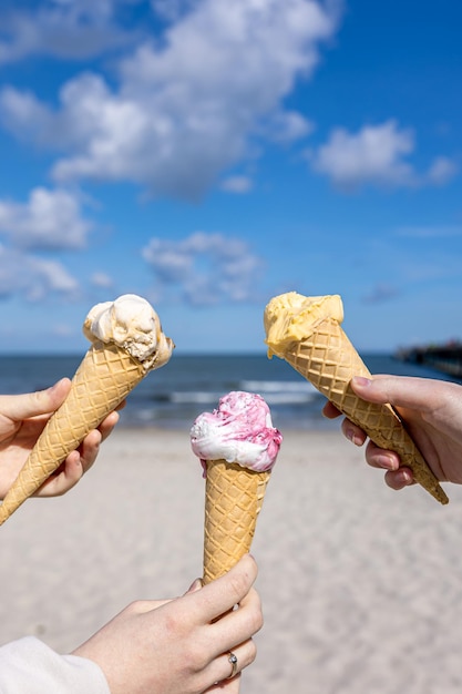 Free photo ice cream in waffle cones in female hands on the background of the sea