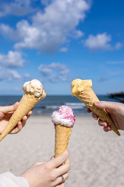 海の背景に女性の手でワッフルコーンのアイスクリーム