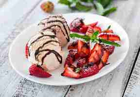 Foto gratuita gelato con fragole e cioccolato su un piatto bianco