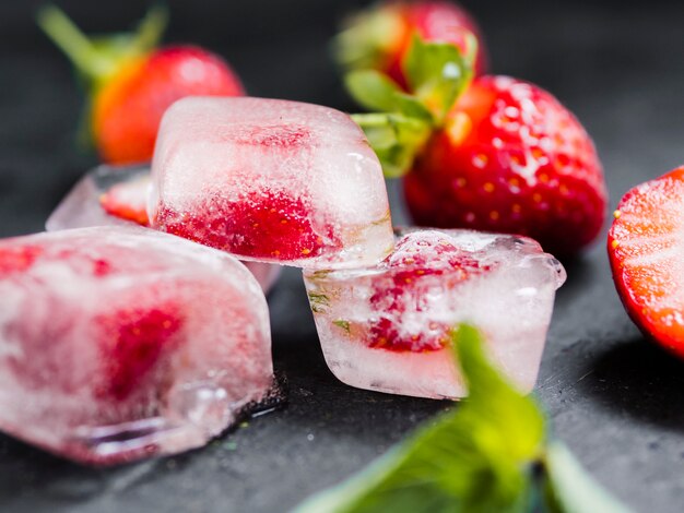 Ice cubes with berries on dark table