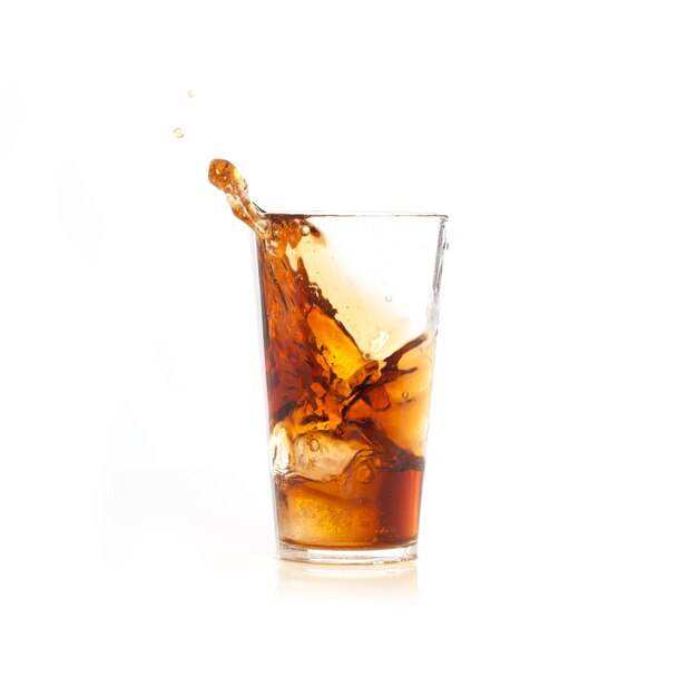 茶色の飲み物が入ったグラスに氷が落ちる