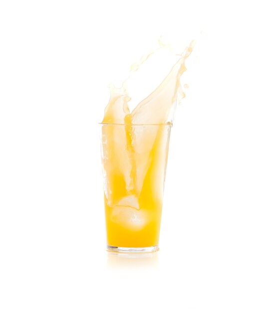 Лед падают в стакан с напитком желтого