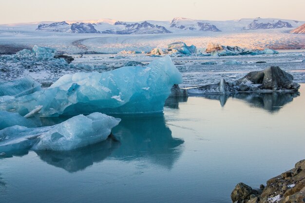 アイスランドの雪に覆われたヨークルサルロンの凍った水の近くの氷山