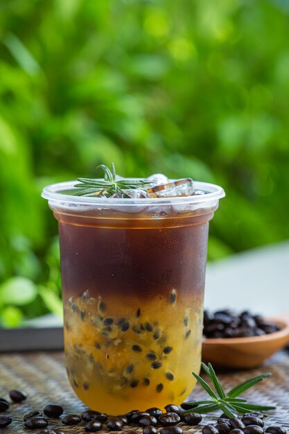 Iced black coffee with passion fruit on wooden surface