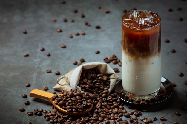 Iced coffee in a tall glass with cream topped with iced coffee decorated with coffee beans.