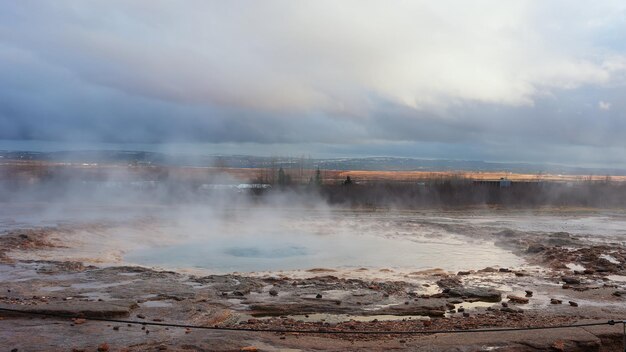 Icelandic geyser in panoramic scenery near reykjavik, holes erupting and creating beautiful fountain with hot water and steam. Scandinavian crater with jet in iceland, landscape. Handheld shot.