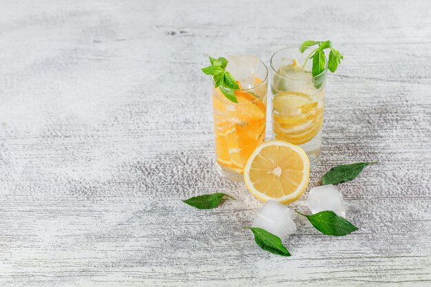 Icy detox water in glass with orange, lemon, mint high angle view on a grunge background