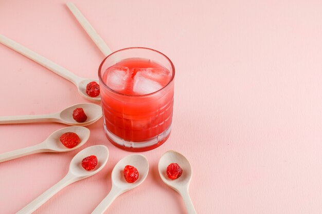 Icy juice in a glass with dried cherry high angle view on a pink surface