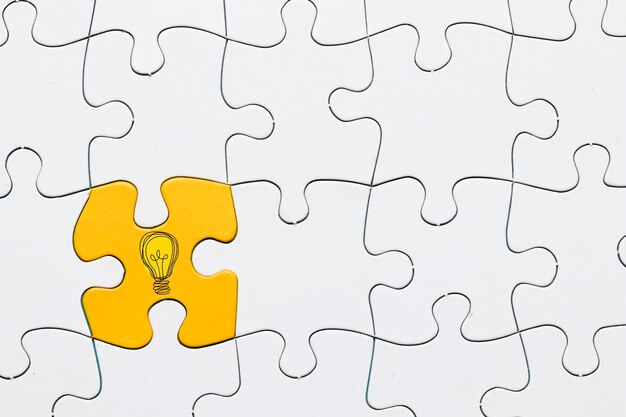 Idea icon on yellow puzzle piece connected with white grid puzzle backdrop