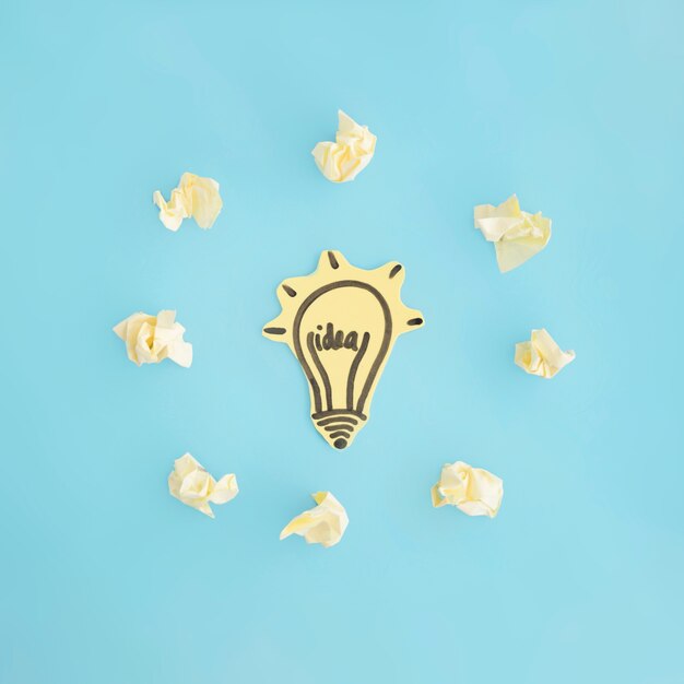 Idea light bulb surrounded with crumpled paper on blue background