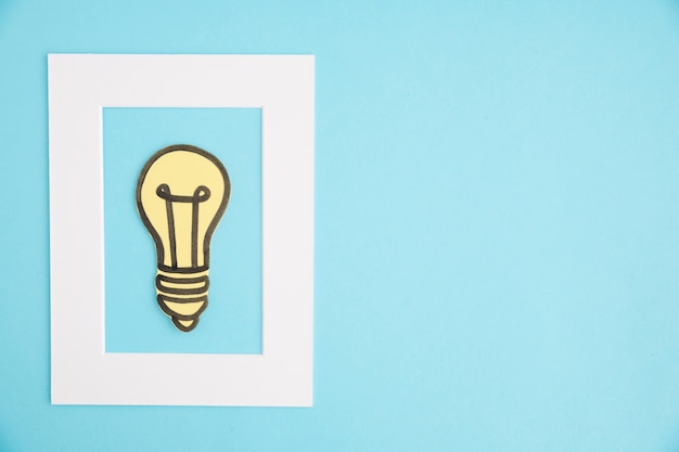 Free photo idea light bulb white frame on blue backdrop