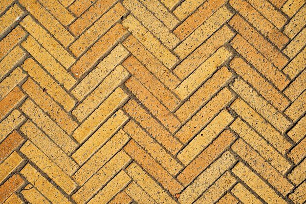 바탕 화면을 위한 간단한 벽지의 아이디어는 오래된 벽돌 세라믹 조약돌의 헤링본 대각선 질감 추상적 배경의 노란색 벽돌로 만든 직사각형 타일 패턴입니다.