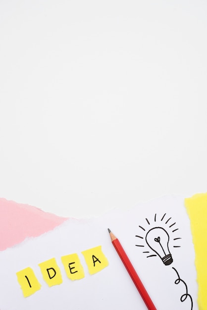 Idea text and hand drawn light bulb with pencil on paper over white backdrop