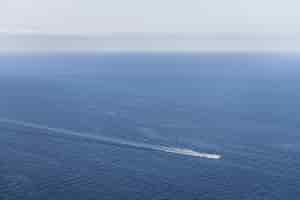 Foto gratuita vista idilliaca di una barca in un oceano blu con uno skyline chiaro - perfetta per la carta da parati