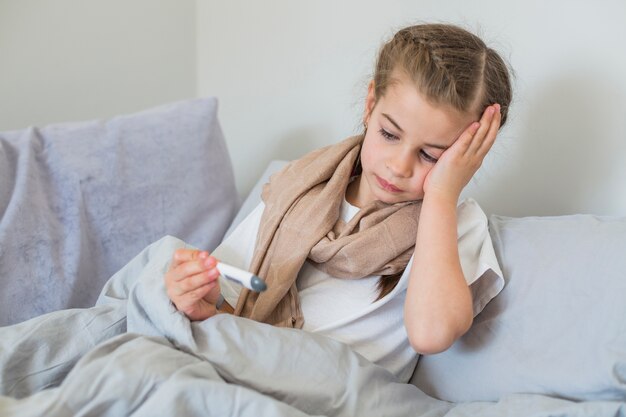 Ill girl using thermometer