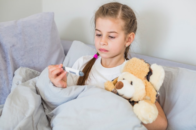 Ill girl using thermometer