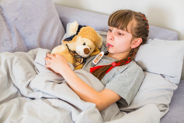 Ill girl using thermometer