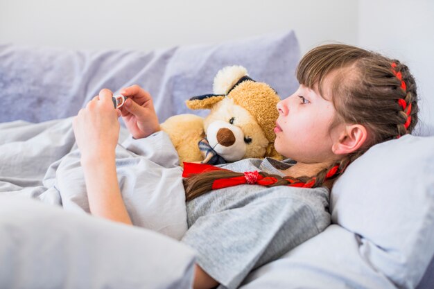 Ill girl using thermometer