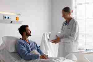 Free photo ill male patient in bed talking to a nurse