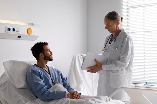 Больной пациент мужского пола в постели разговаривает с медсестрой