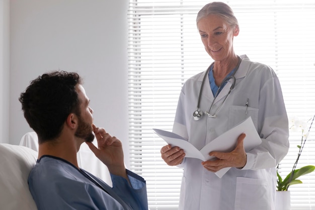 Ill male patient in bed talking to a nurse