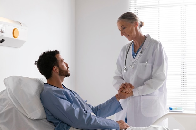 Ill male patient in bed talking to a nurse