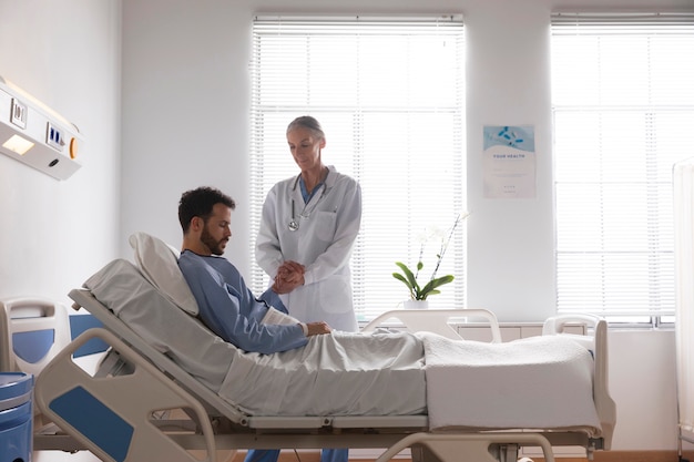 Free photo ill male patient in bed talking to a nurse