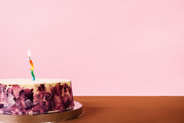 Свеча с подсветкой на вкусном торте на розовом фоне