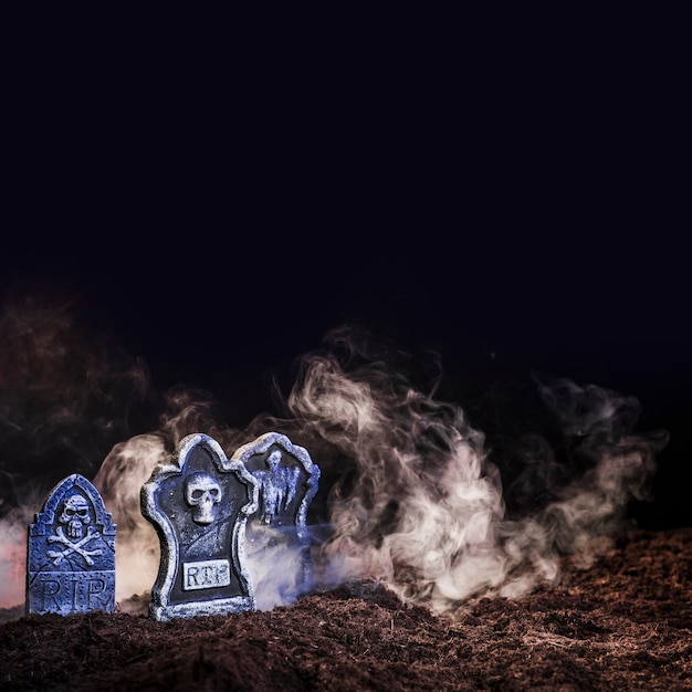 Illuminated gravestones between fog on ground