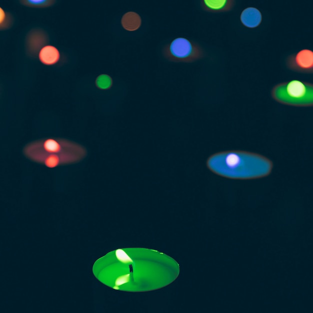 Illuminated multi colored candles on dark background