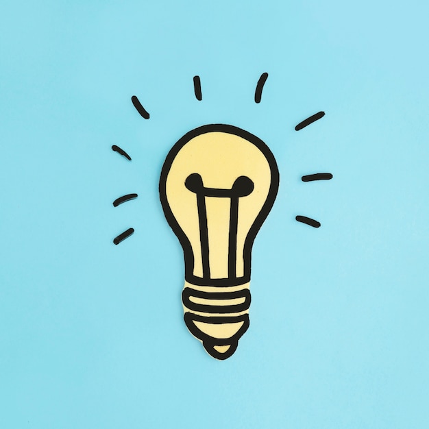 Illuminated paper cutout yellow light bulb on blue background