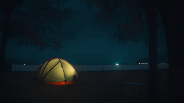 Illuminated tent on the beach under the beautiful mysterious night sky