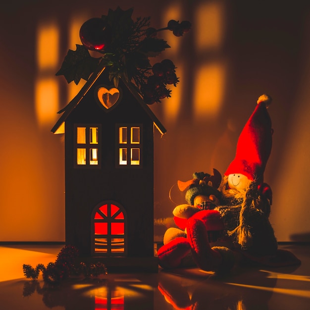 Illuminated wooden house with rag dolls