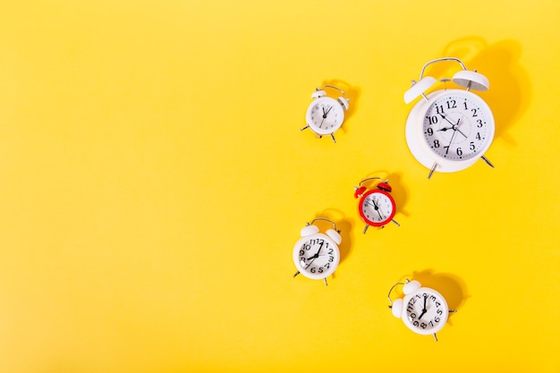 Image of 4 and 1 red alarm clocks on isolated orange wall,