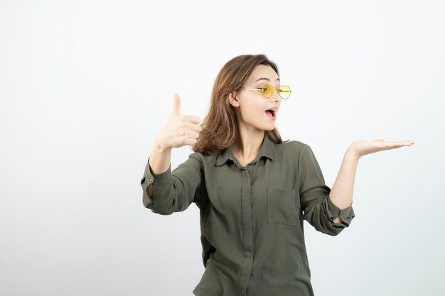 Image of adorable girl in glasses giving thumbs up over white. High quality photo