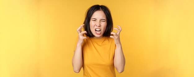 화난 아시아 여성이 화난 얼굴 표정으로 서서 소리를 지르며 저주하는 이미지