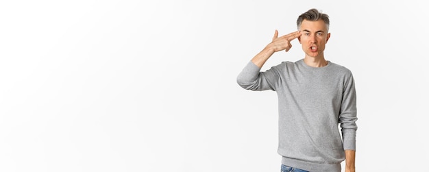 Free photo image of annoyed and fed up middleaged man showing finger gun sign near head shooting himself with p