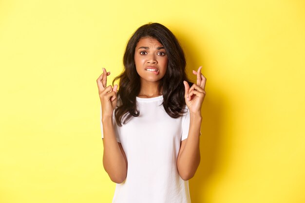 Image of anxious and hopeful africanamerican woman waiting for news with fingers crossed making wish