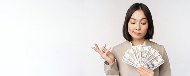 현금 달러를 보여주고 흰색 배경 위에 양복을 입고 생각하는 아시아 기업 여성 행복한 여성 사업가의 이미지