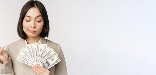 Image of asian corporate woman happy businesswoman showing money cash dollars and thinking standing