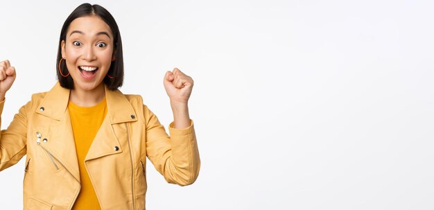 Image of asian woman dancing and smiling happy celebrating victory triumphing standing over white background copy space