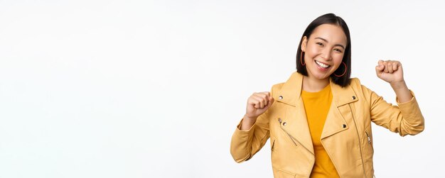 Image of asian woman dancing and smiling happy celebrating victory triumphing standing over white background copy space