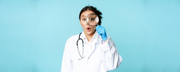 아시아 여성 의사 또는 간호사의 이미지가 돋보기를 통해 보고 놀란 것을 발견했습니다.