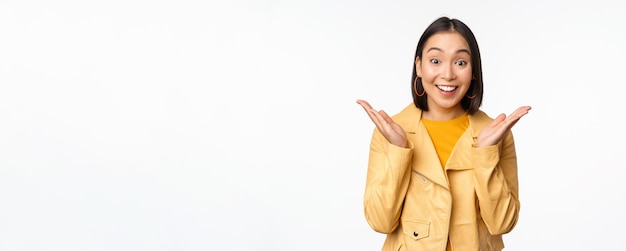 Image of asian woman looking surprised amazed reaction shocked face standing over white background