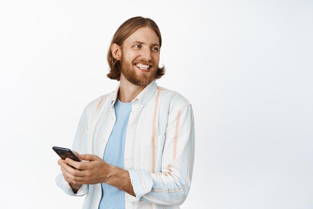 笑っている魅力的なひげを生やした男性の画像、プロモーションコピースペースを右に見て、携帯電話を使用して、スマートフォンとチャットし、携帯電話会社の広告。