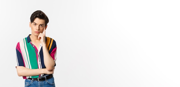 Image of attractive young man staring at camera with reluctant and annoyed emotion standing over white background