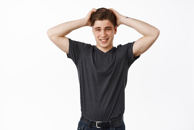 Image of awkward teenage boy guy scratch head and smiling blushing and looking embarrassed dont know what to say has problem standing against white background