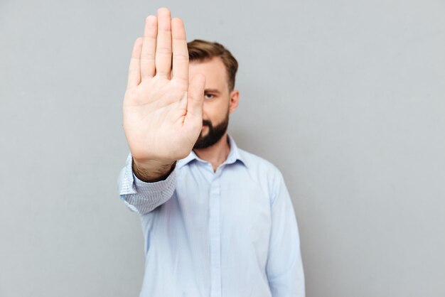 Image of Bearded man in business clothes showing stop gesture